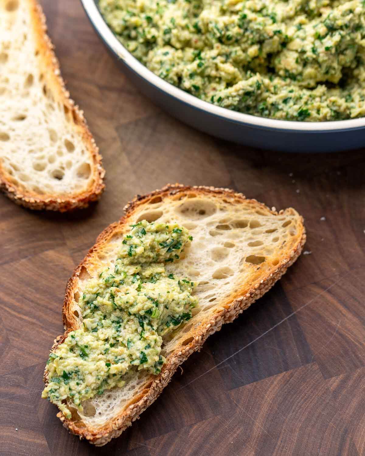 Artichoke pesto spread onto a piece of bread.