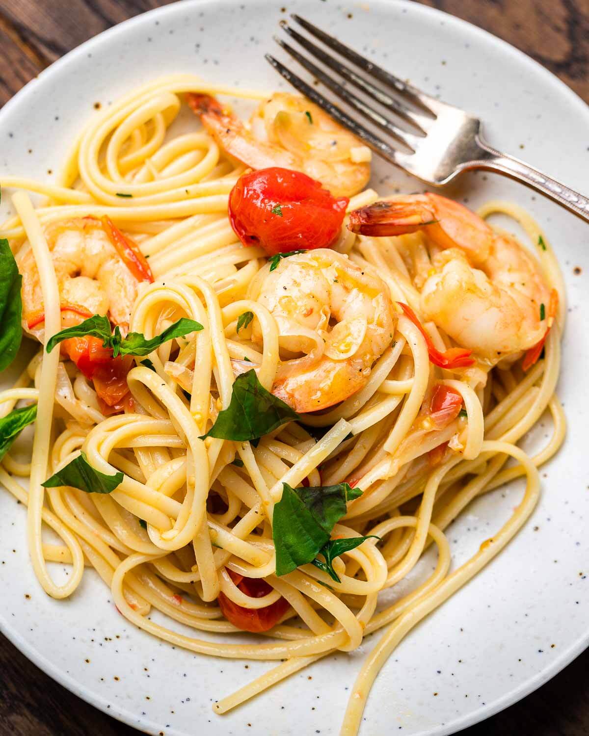 Shrimp tomato basil pasta in white plate with fork.