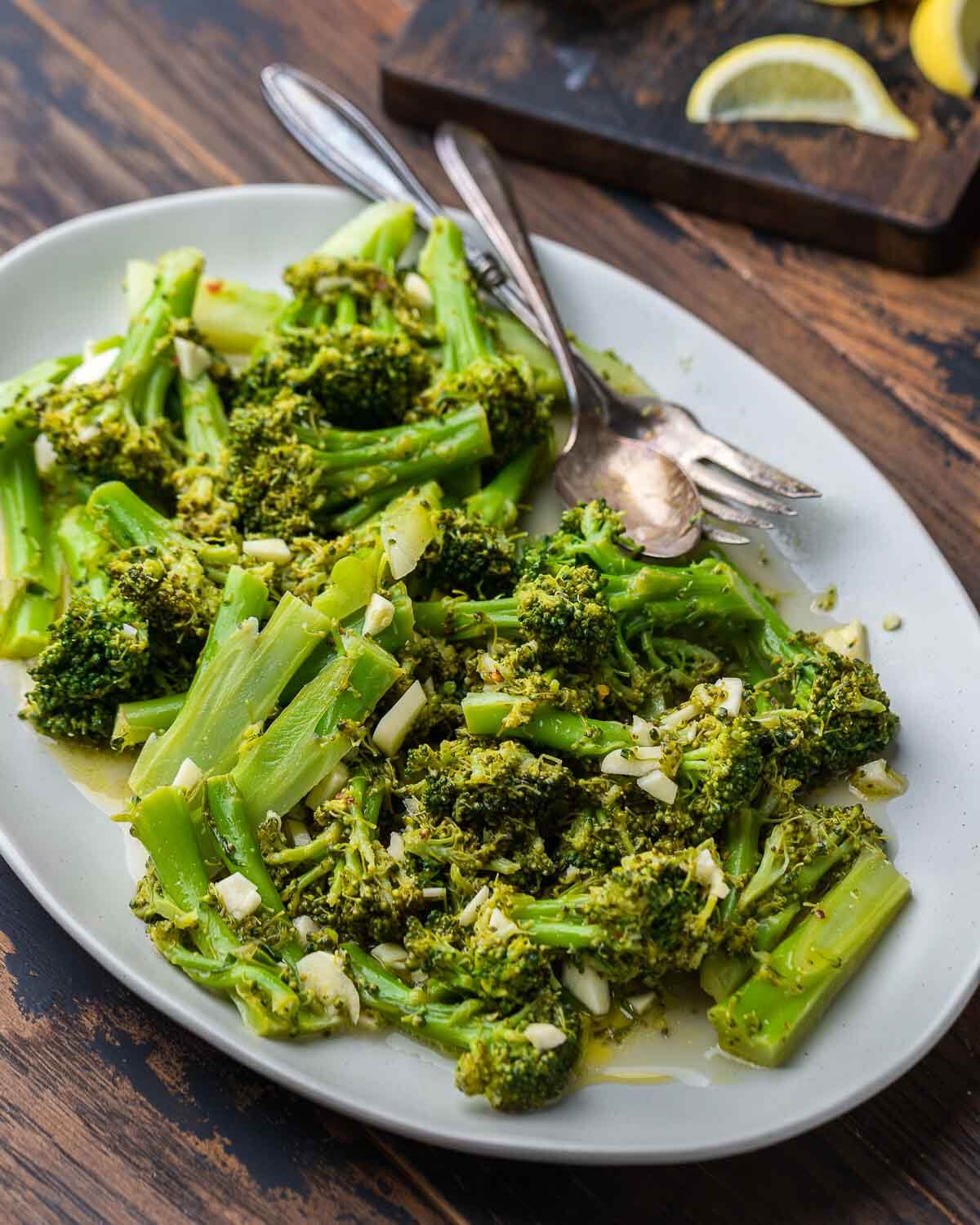 Italian broccoli salad in platter with cut lemon wedge in the background.