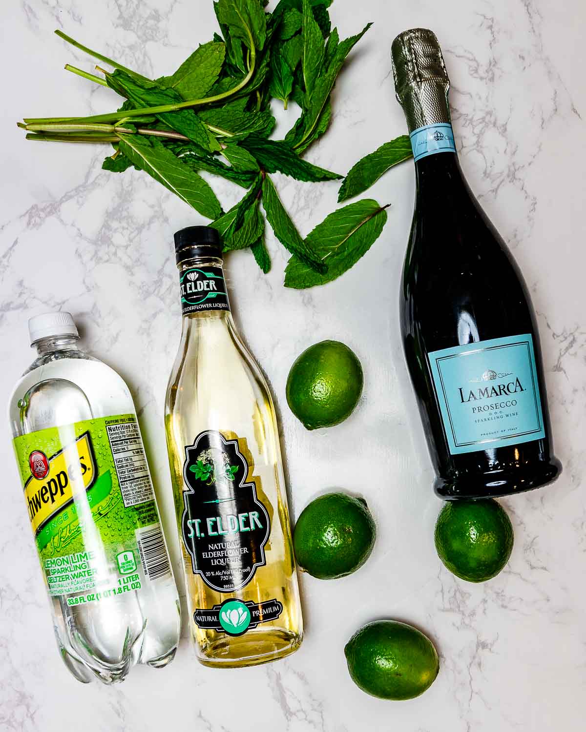 Ingredients shown: mint, prosecco, lemon lime seltzer, elderflower liqueur, and limes.