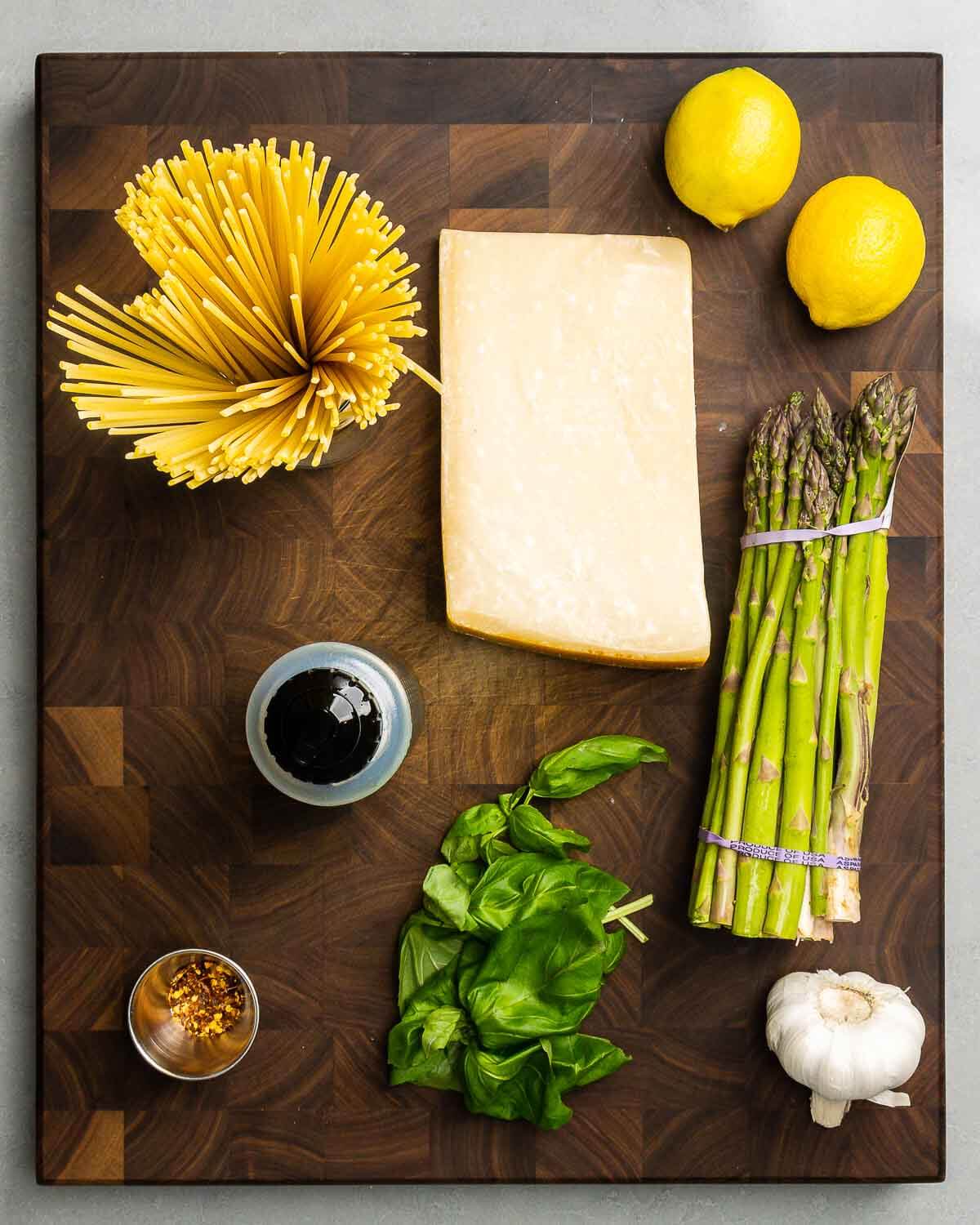 Ingredients shown: spaghetti, parmesan, lemons, asparagus, olive oil, hot red pepper flakes, basil, and garlic.