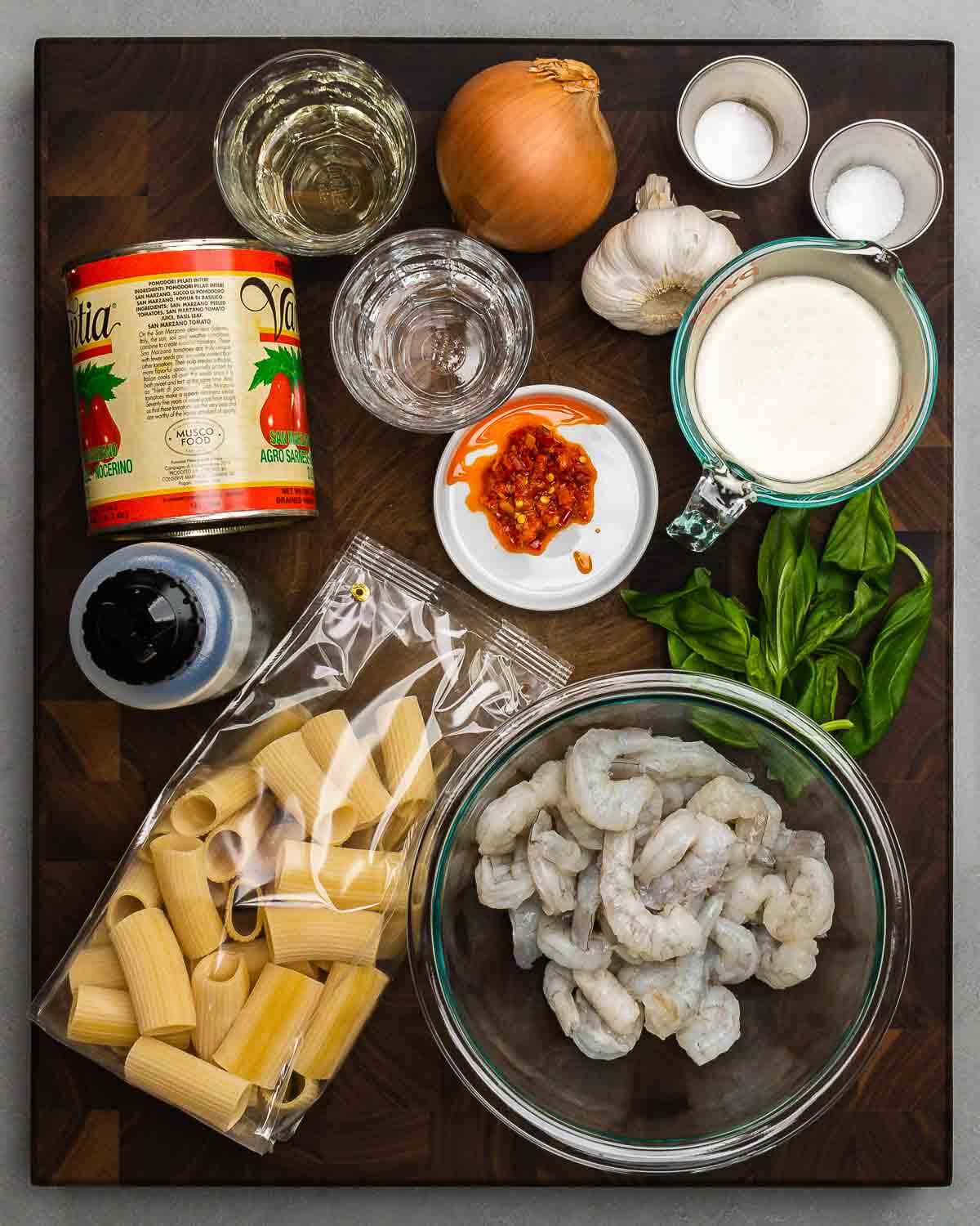 Ingredients shown: tomatoes, white wine, vodka, garlic, salt, baking soda, Calabrian chili paste, heavy cream, olive oil, rigatoni, basil, and shrimp.