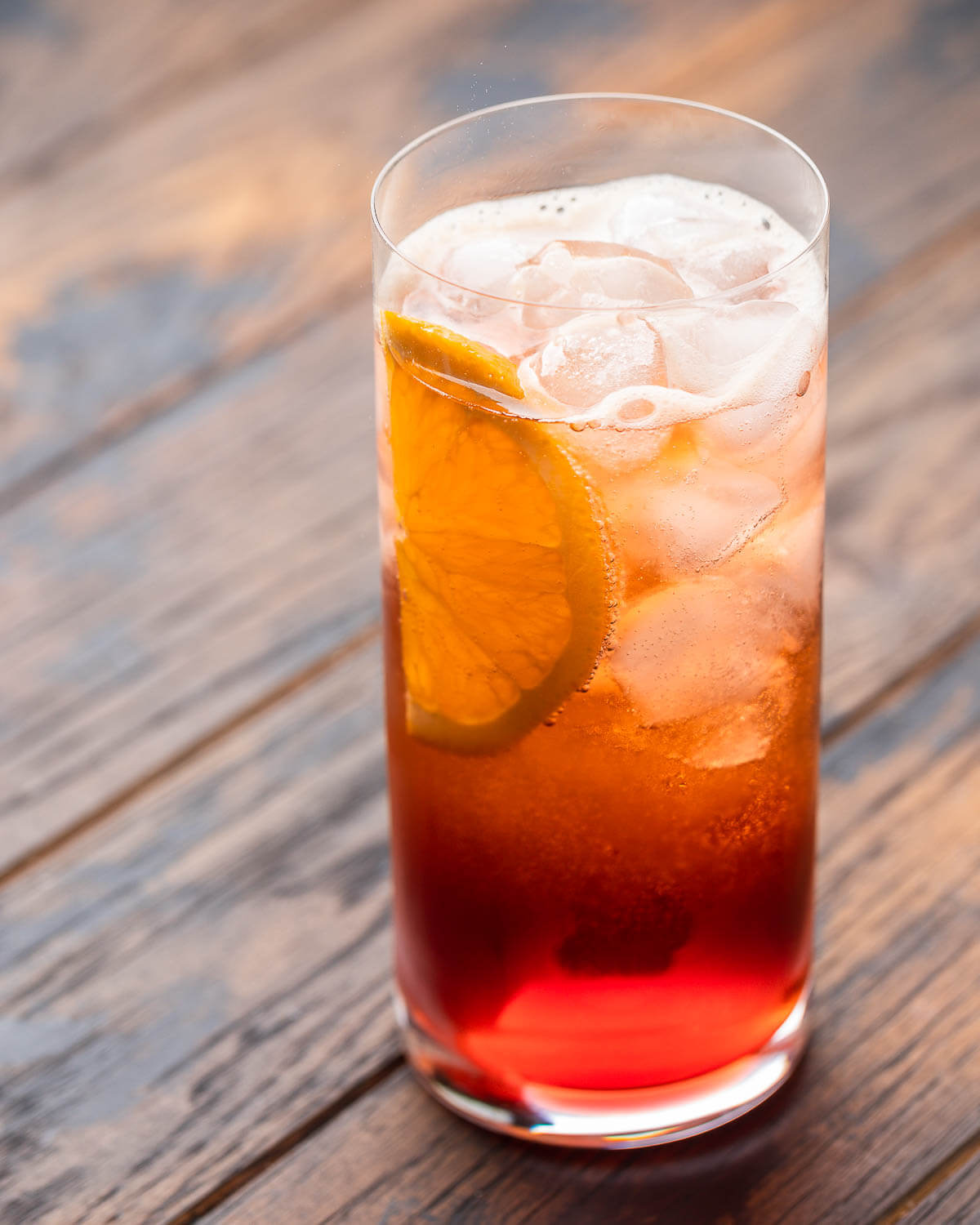 Highball glass with Americano cocktail in sunlight.