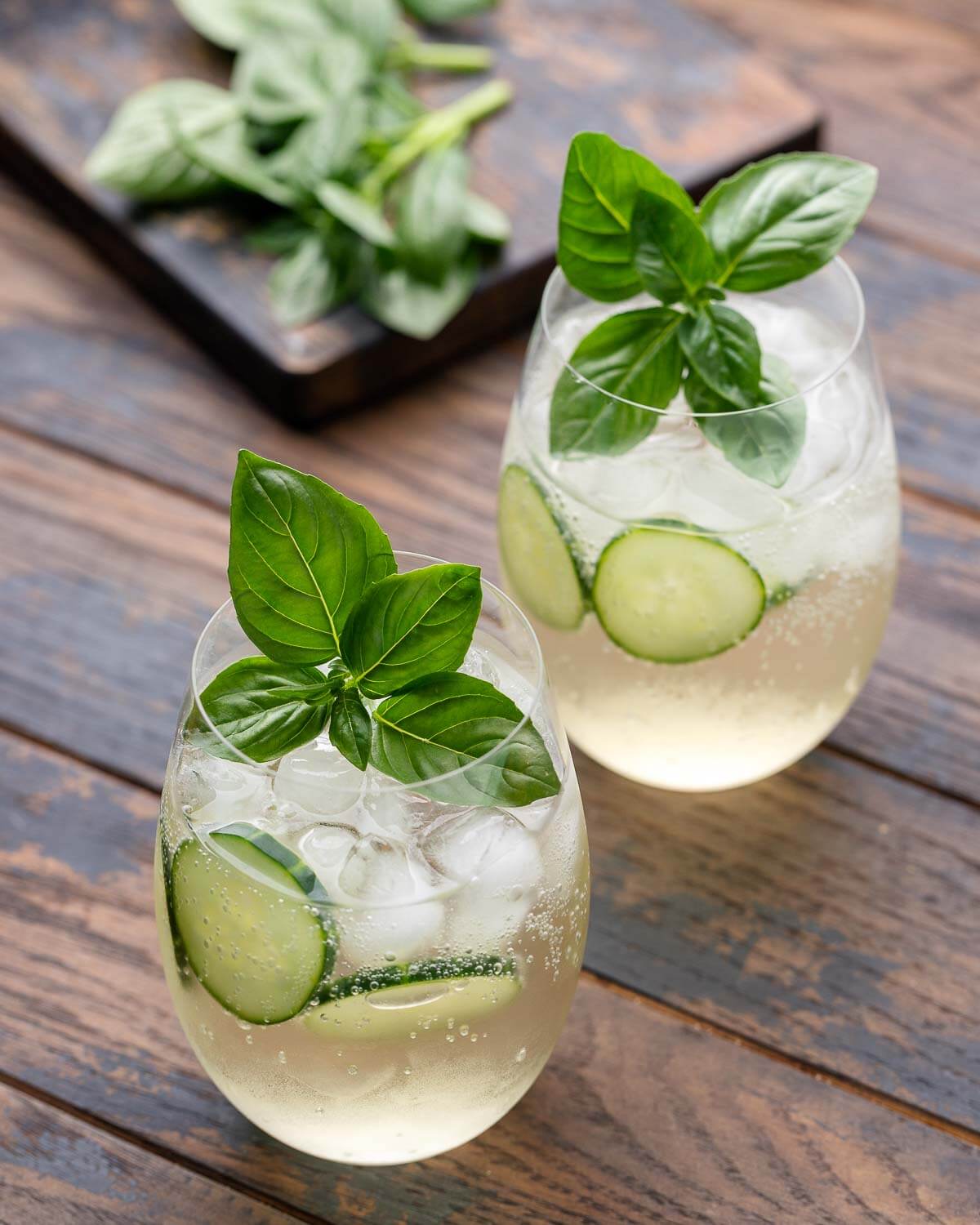 Two glasses of lillet spritz with basil and cucumber.