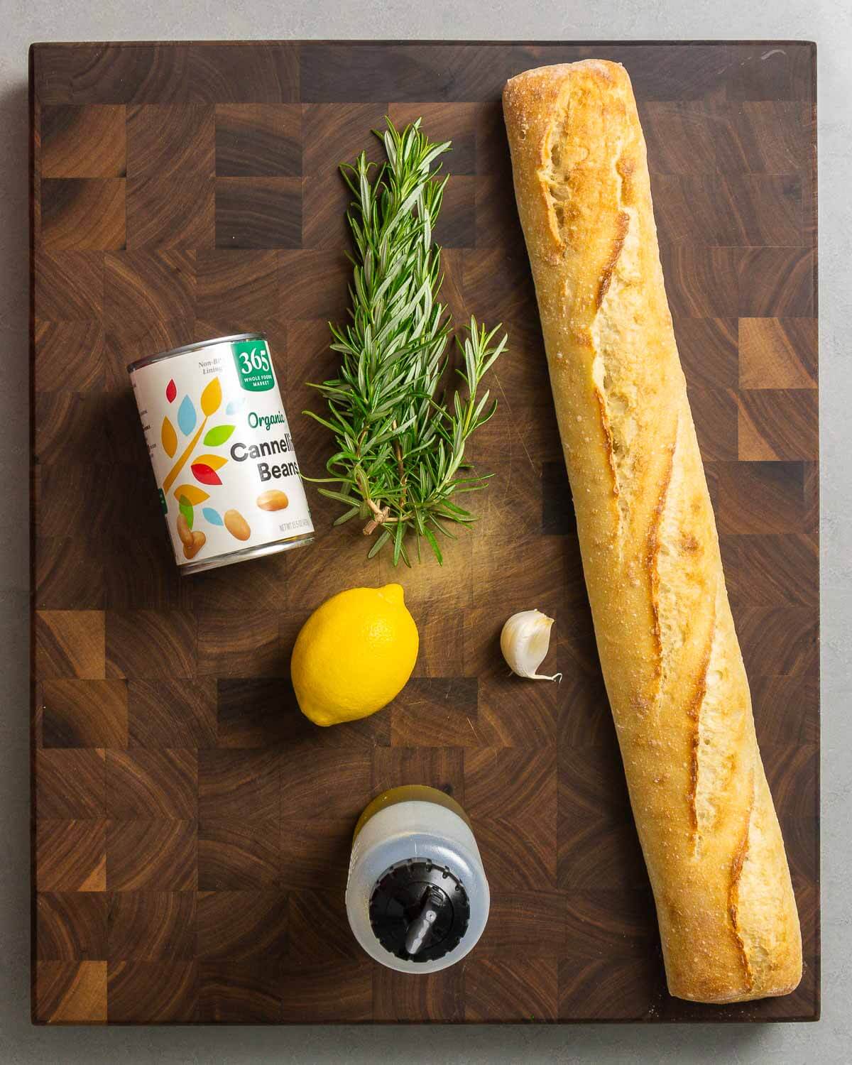 Ingredients shown: cannelini beans, rosemary, baguette, lemon, garlic, and extra virgin olive oil.