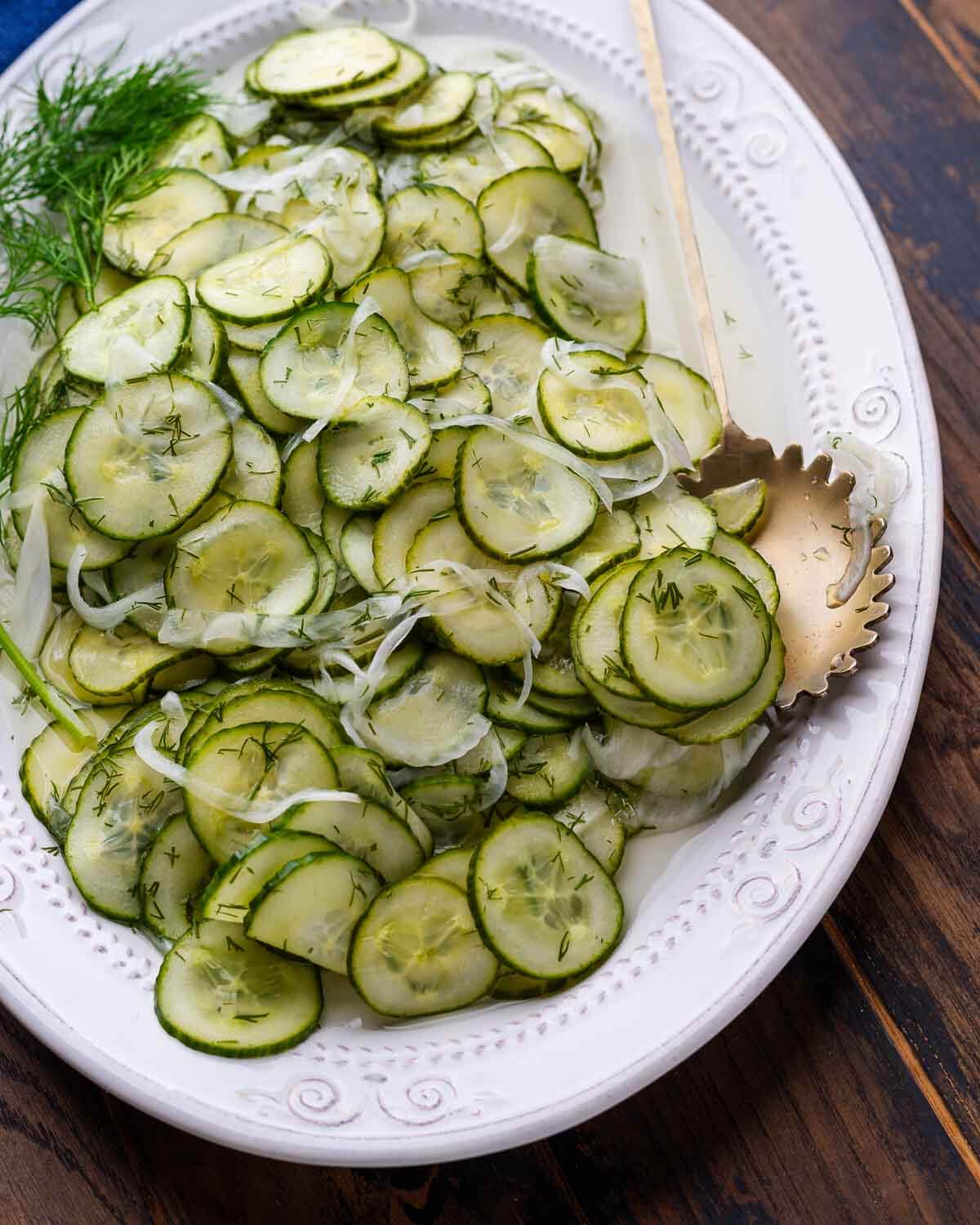 Overhead shot of white platter with deli cucumber salad.