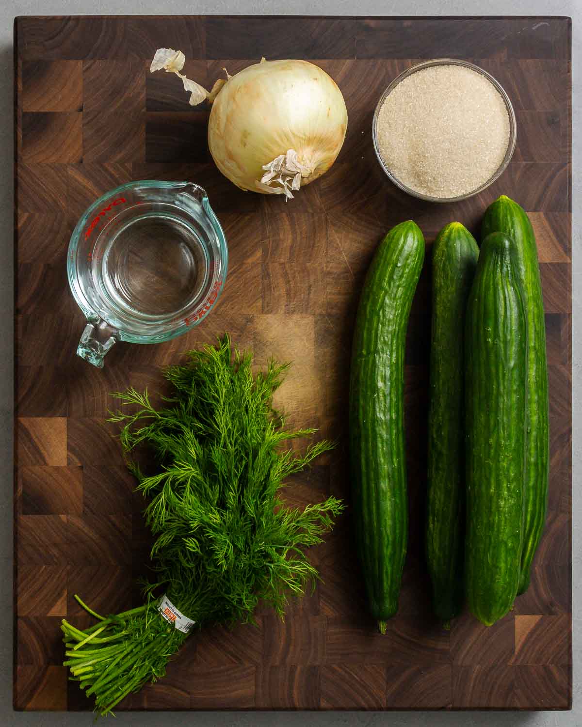 Ingredients shown: onion, sugar, white vinegar, dill, and cucumbers.