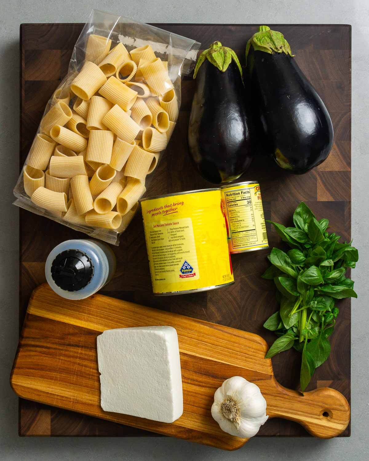 Ingredients shown: pasta, eggplants, extra virgin olive oil, plum tomatoes and tomato paste, basil, ricotta salata, and garlic.