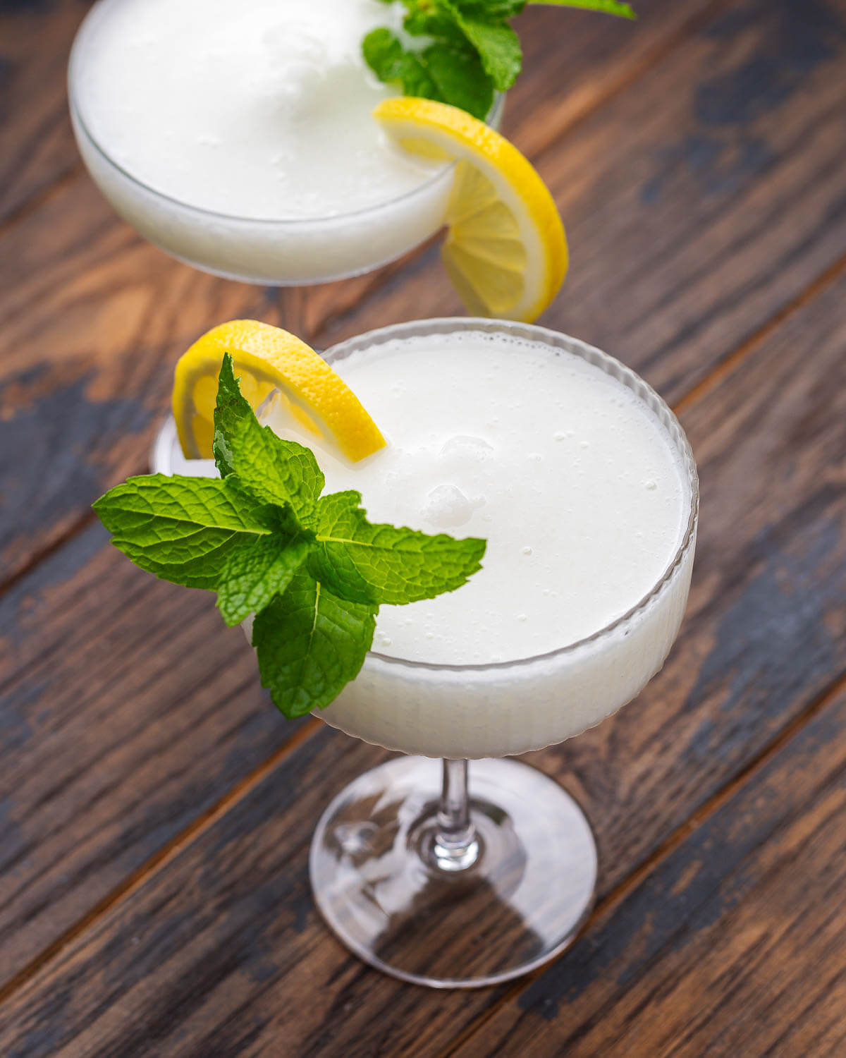 Two sgroppino cocktails in coupe glasses with mint and lemon garnish.