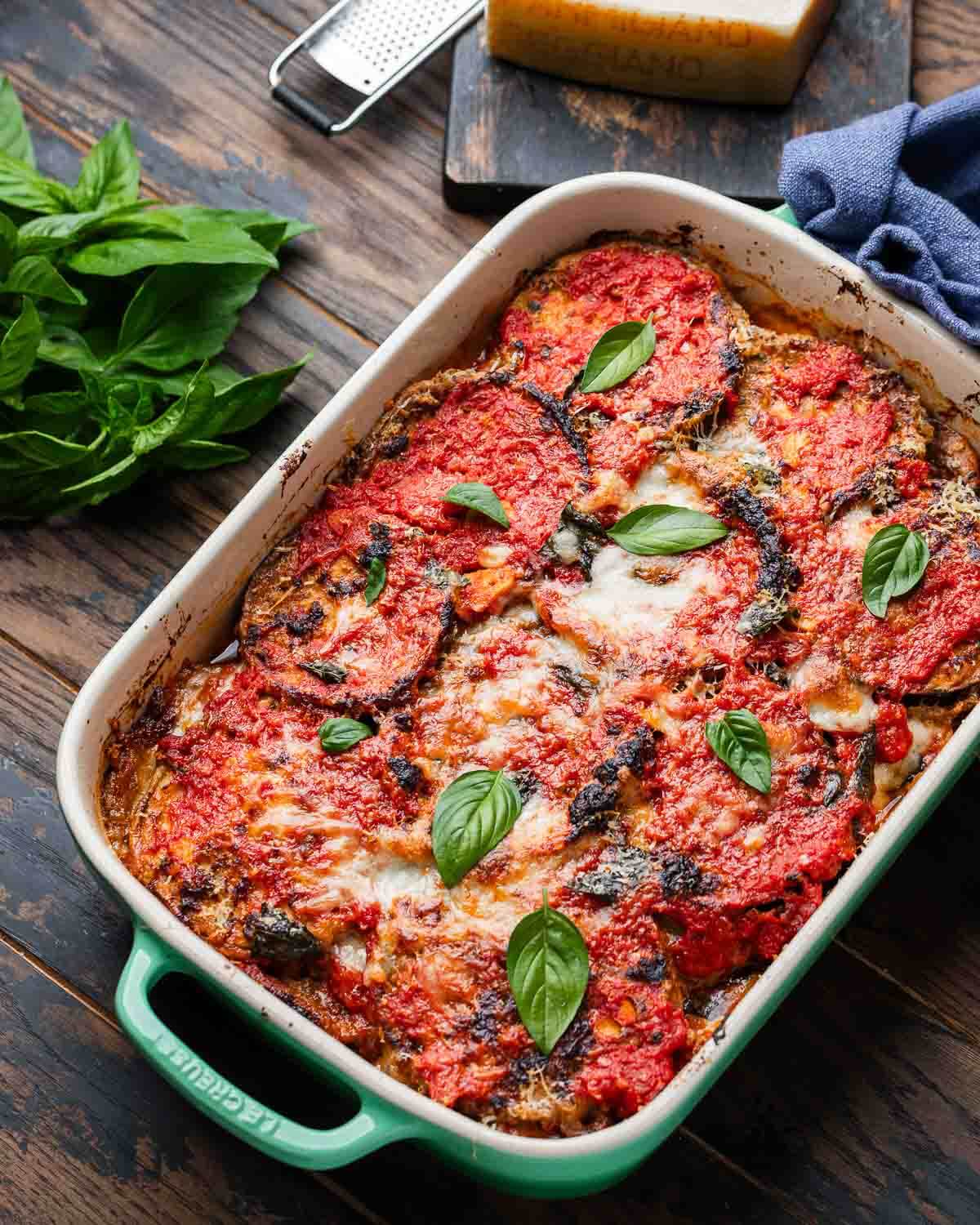 Large table with baking dish of Neapolitan style eggplant parmigiana.