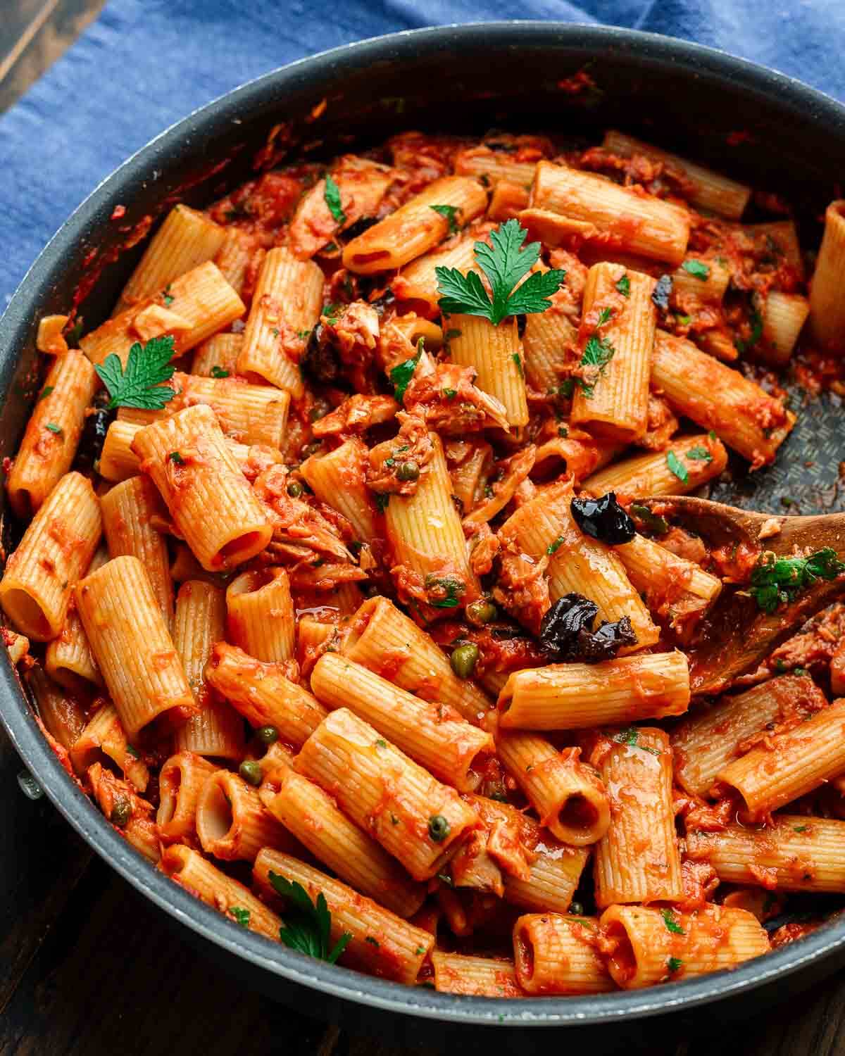 Rigatoni al tonno in large black pan on blue napkin.