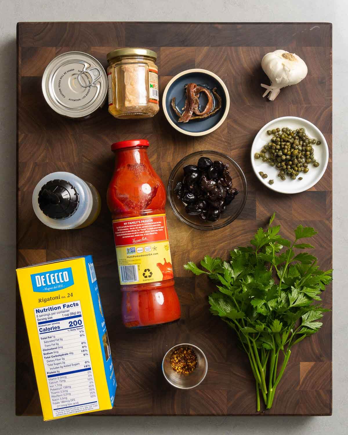 Ingredients shown: tuna in oil, anchovy, garlic, olive oil, passata, olives, capers, rigatoni, hot red pepper flakes, and parsley.