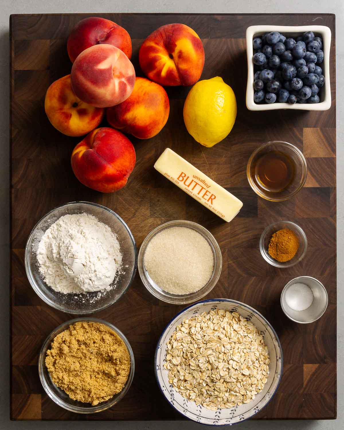 Ingredients shown: peaches, lemon, blueberries, flour, sugar, butter, vanilla, cinnamon, salt, brown sugar, and oats.