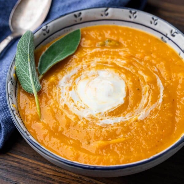 Roasted butternut squash soup in white and blue bowl with sage leave garnish for featured image.