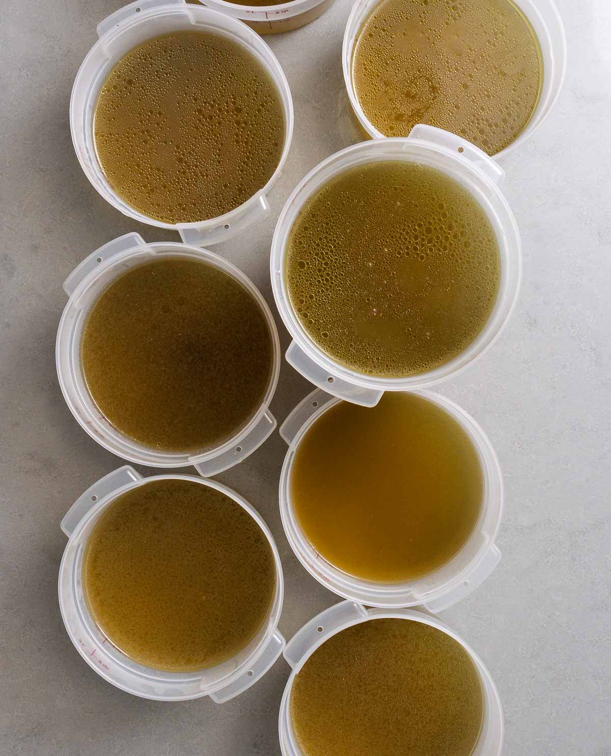 Multiple containers of chicken stock on granite countertop.