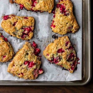 Cranberry orange scones on top of parchment paper lined baking sheet.