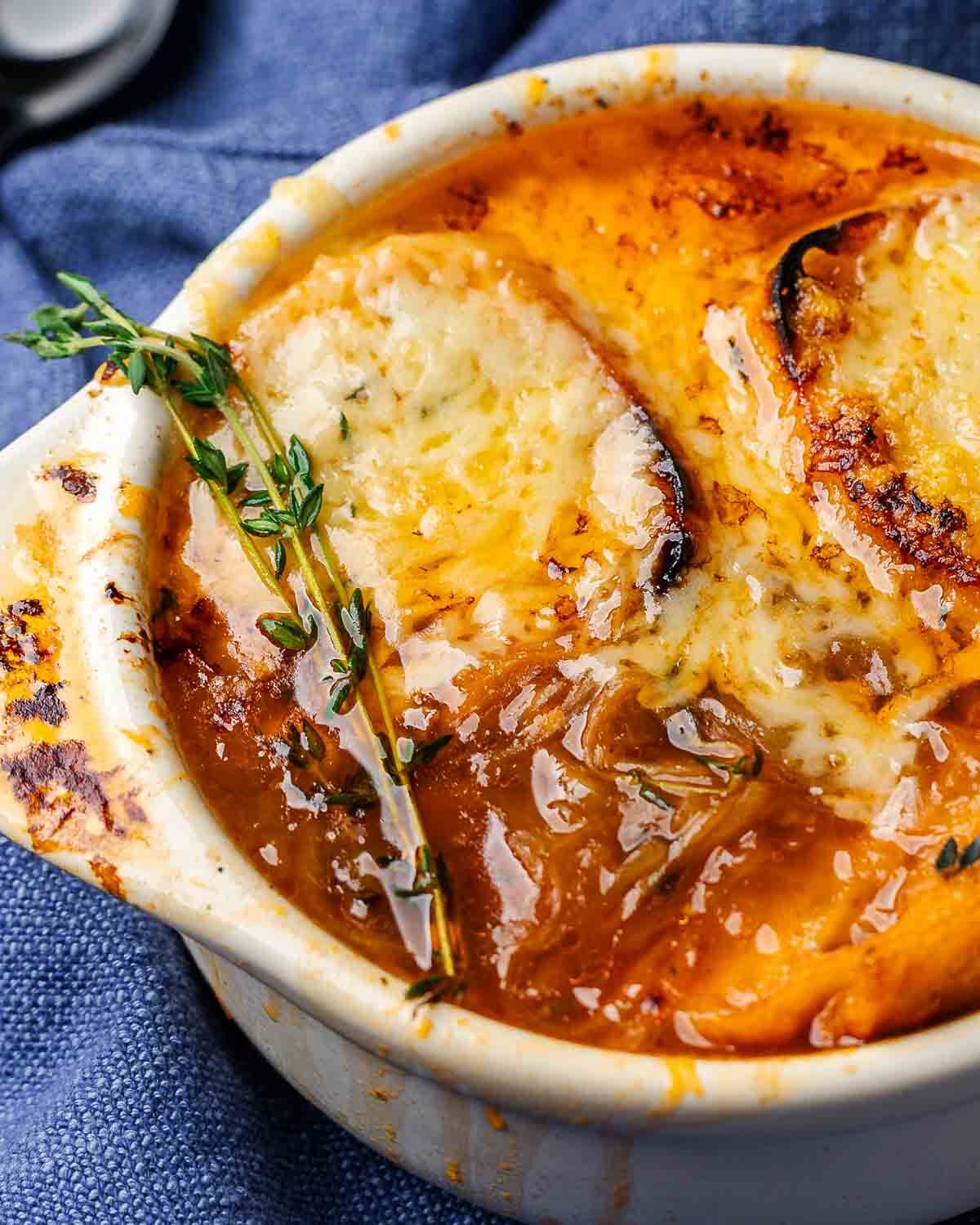 Closeup shot of French onion soup in white bowl.