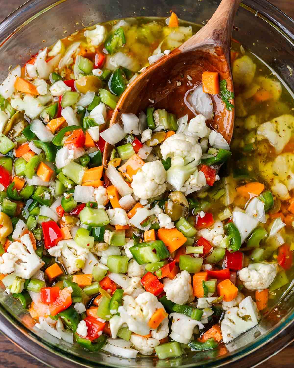 Large bowl of giardiniera with wooden ladle.