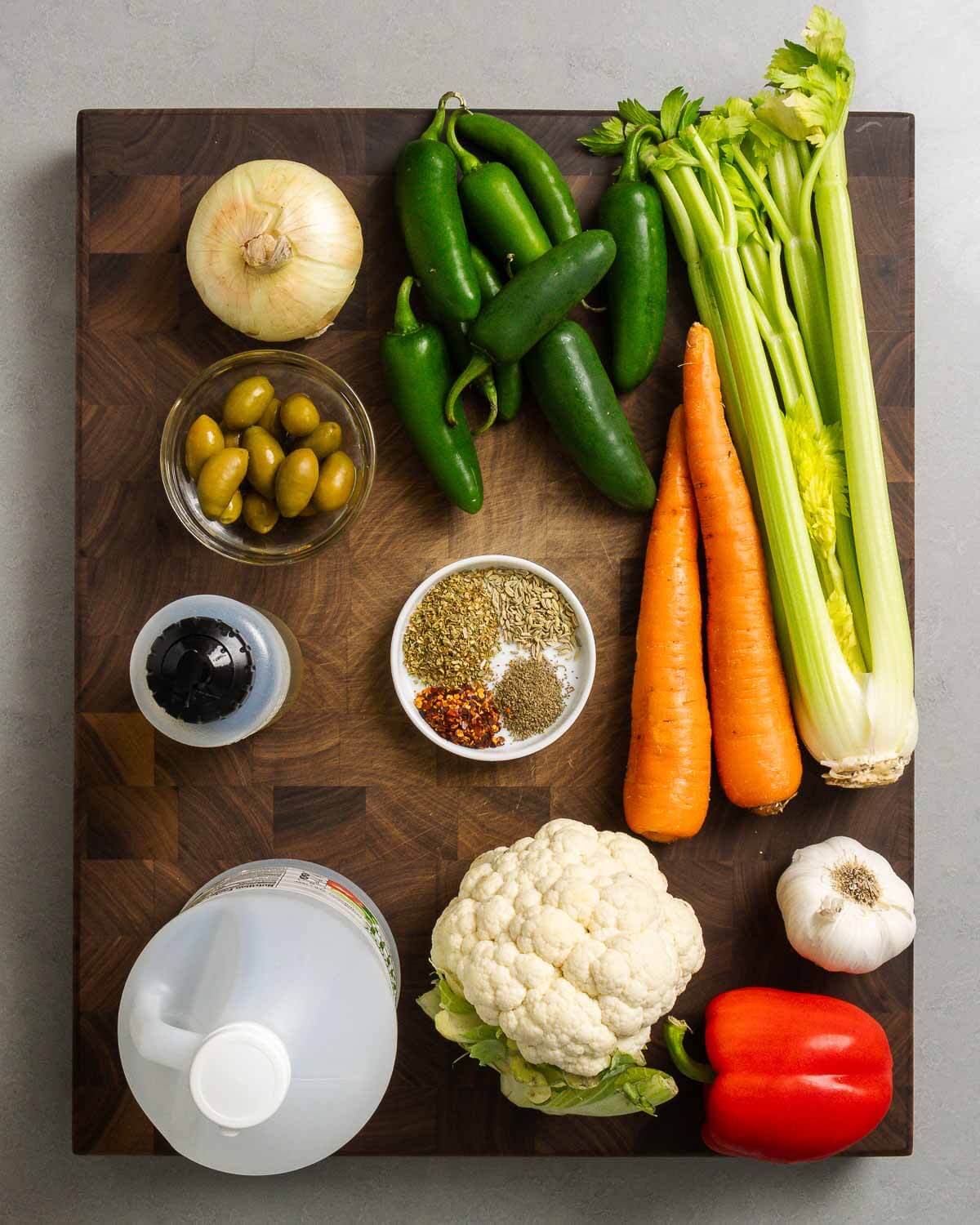 Ingredients shown: onion, hot peppers, carrot, celery, olives, olive oil, spices, vinegar, cauliflower, garlic, and bell pepper.
