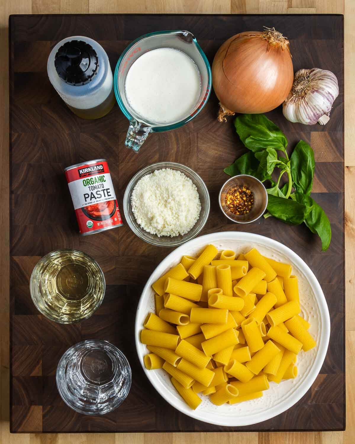 Ingredients shown: olive oil, heavy cream, onion, garlic, basil, tomato paste, Pecorino Romano, hot red pepper flakes, white wine, vodka, and rigatoni pasta.