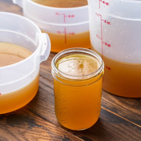 Featured image showing mason jar filled with beef stock along with 3 large containers in the background.