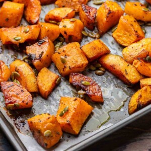 Featured image of roasted butternut squash in grey parchment paper lined baking sheet.