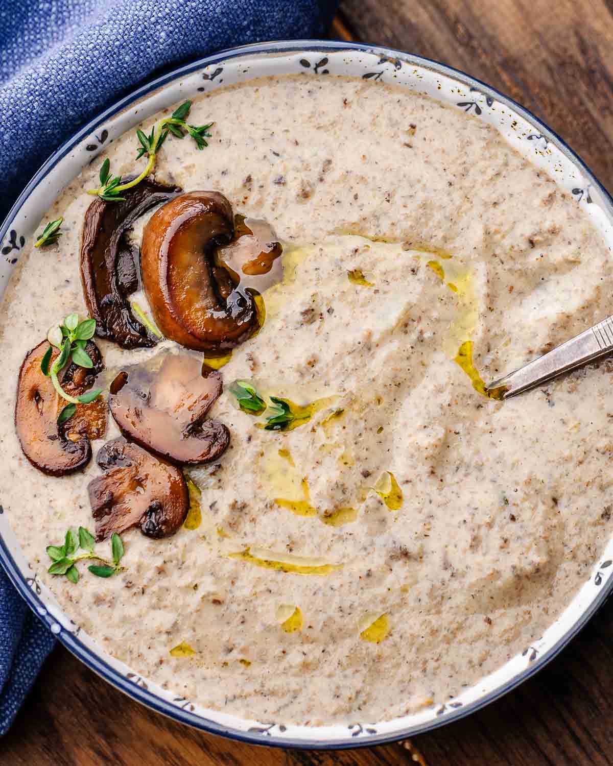 Overhead shot of bowl with creamy mushroom soup and whole sauteed mushrooms and thyme.