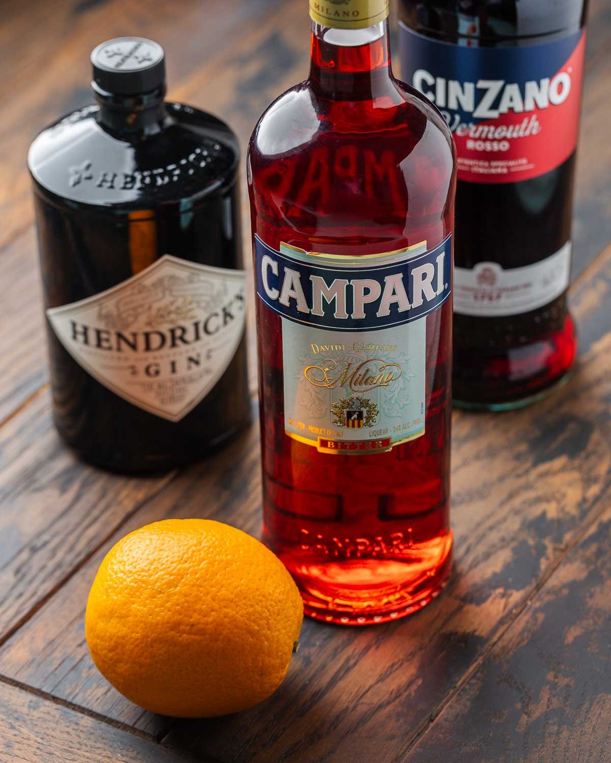 Ingredients shown: gin, Campari, sweet vermouth, and one orange.