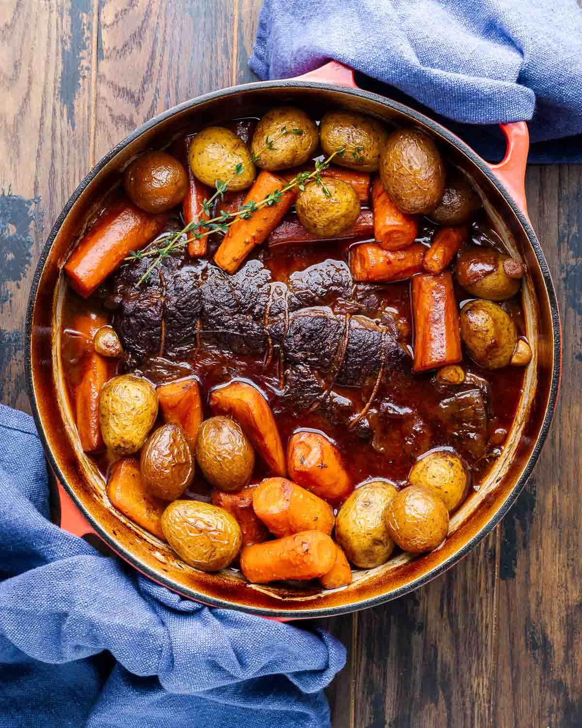 Overhead shot of fully cooked pot roast and vegetables in Dutch oven.