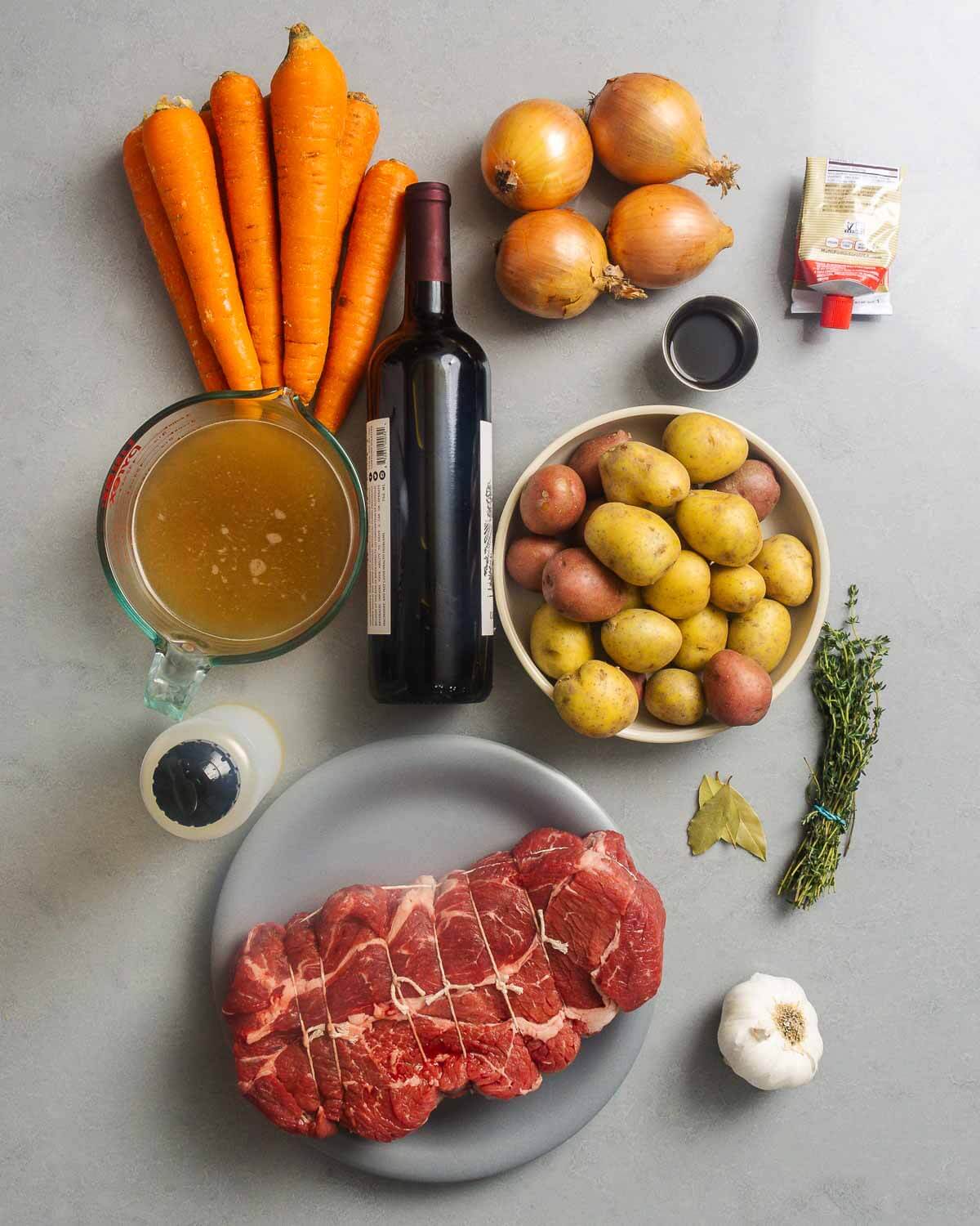 Ingredients shown: carrots, onions, red wine, worcestershire sauce, tomato paste, beef stock, potatoes, olive oil, thyme, bay leaves, chuck roast, and garlic.