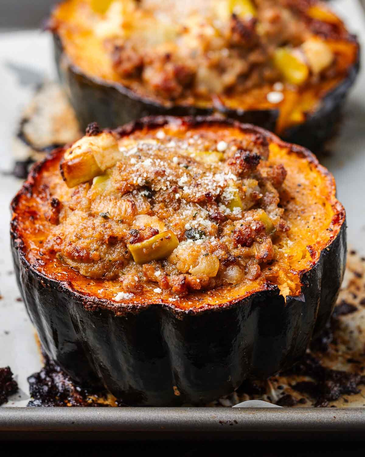 Sausage stuffed acorn squash on baking sheet.