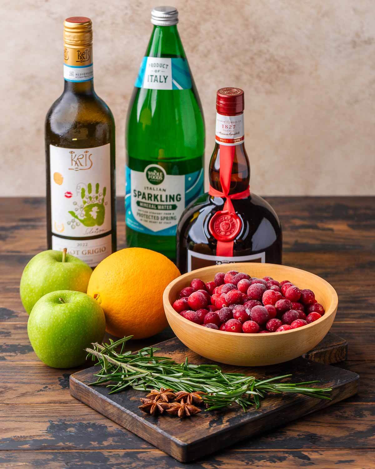Ingredients shown: white wine, sparkling water, Gran Marnier, apples, oranage, cranberries, rosemary, and star anise.