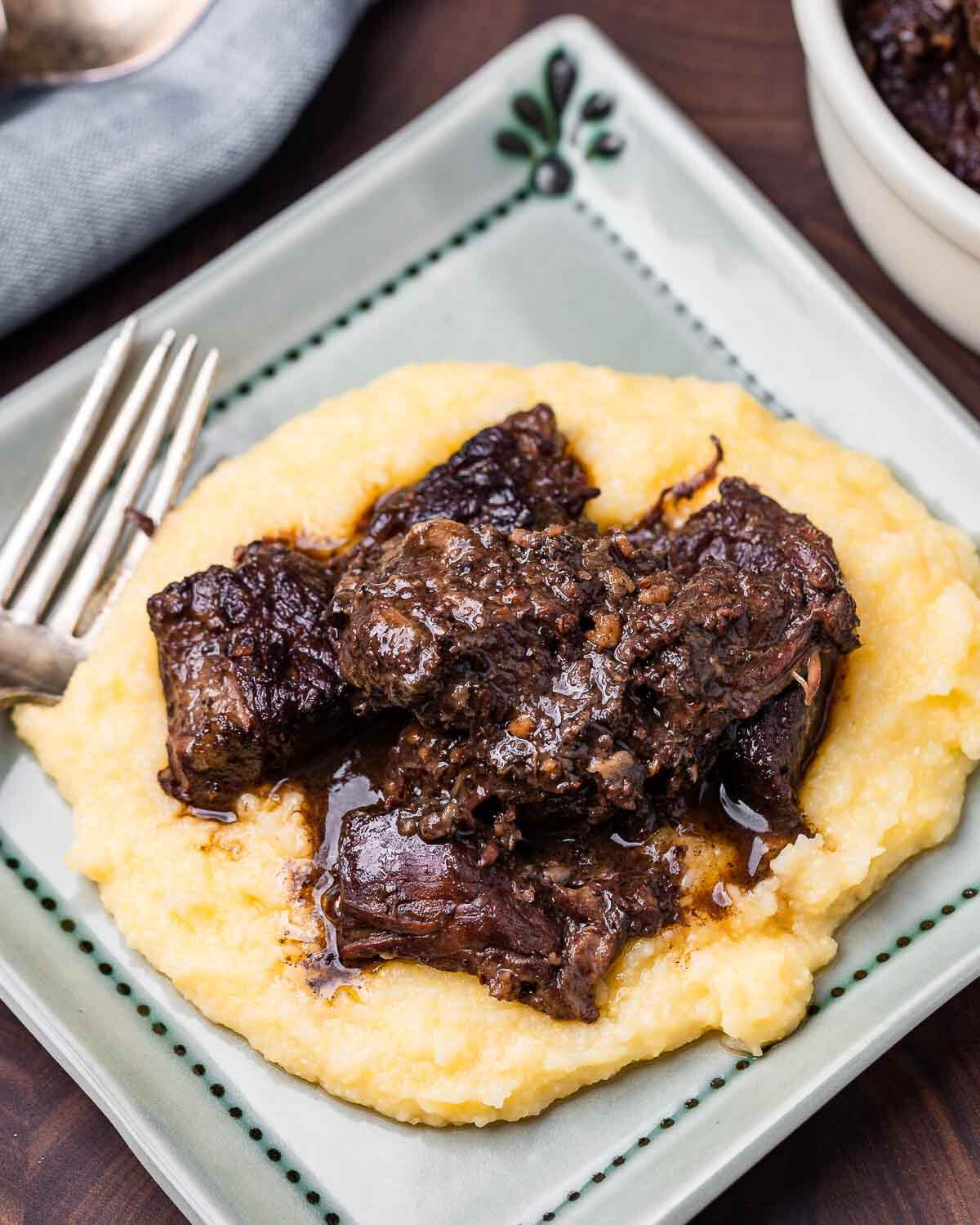 Polenta topped with Tuscan pepper stew in blue plate.