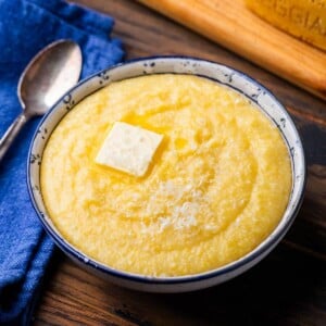 White and blue bowl with creamy polenta topped with butter.