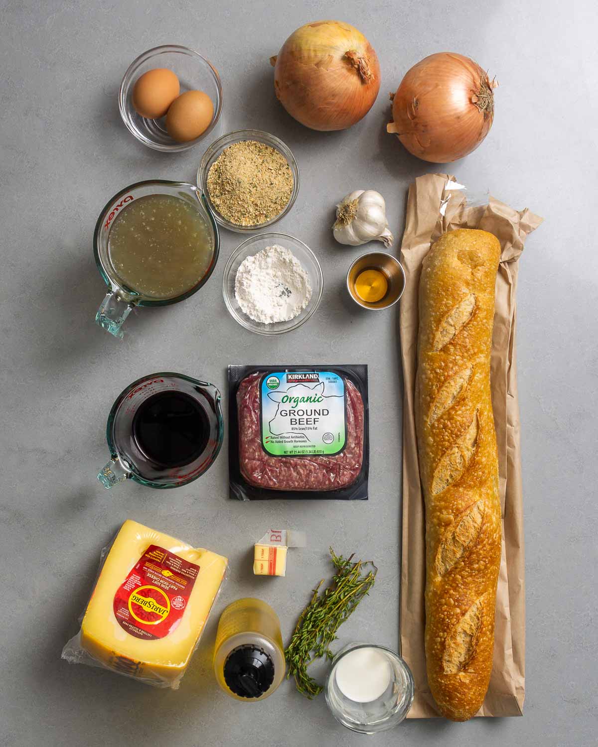 Ingredients shown: eggs, chicken stock, breadcrumbs, flour, onions, garlic, brandy, baguette, red wine, ground beeg, swiss cheese, butter, olive oil, thyme, and milk.