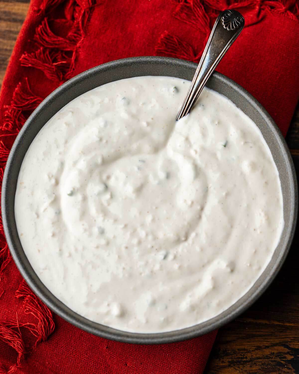 Grey bowl of horseradish sauce on top of red napkin.