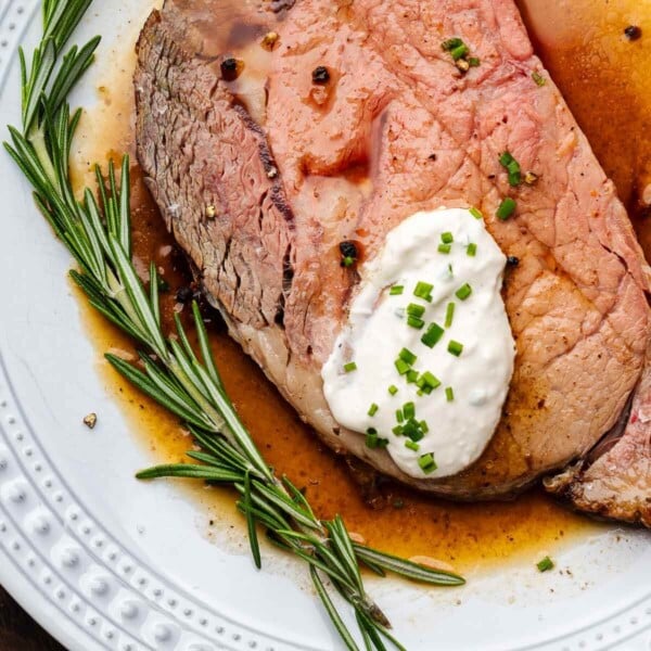 Horseradish sauce on top of prime rib with rosemary garnish.