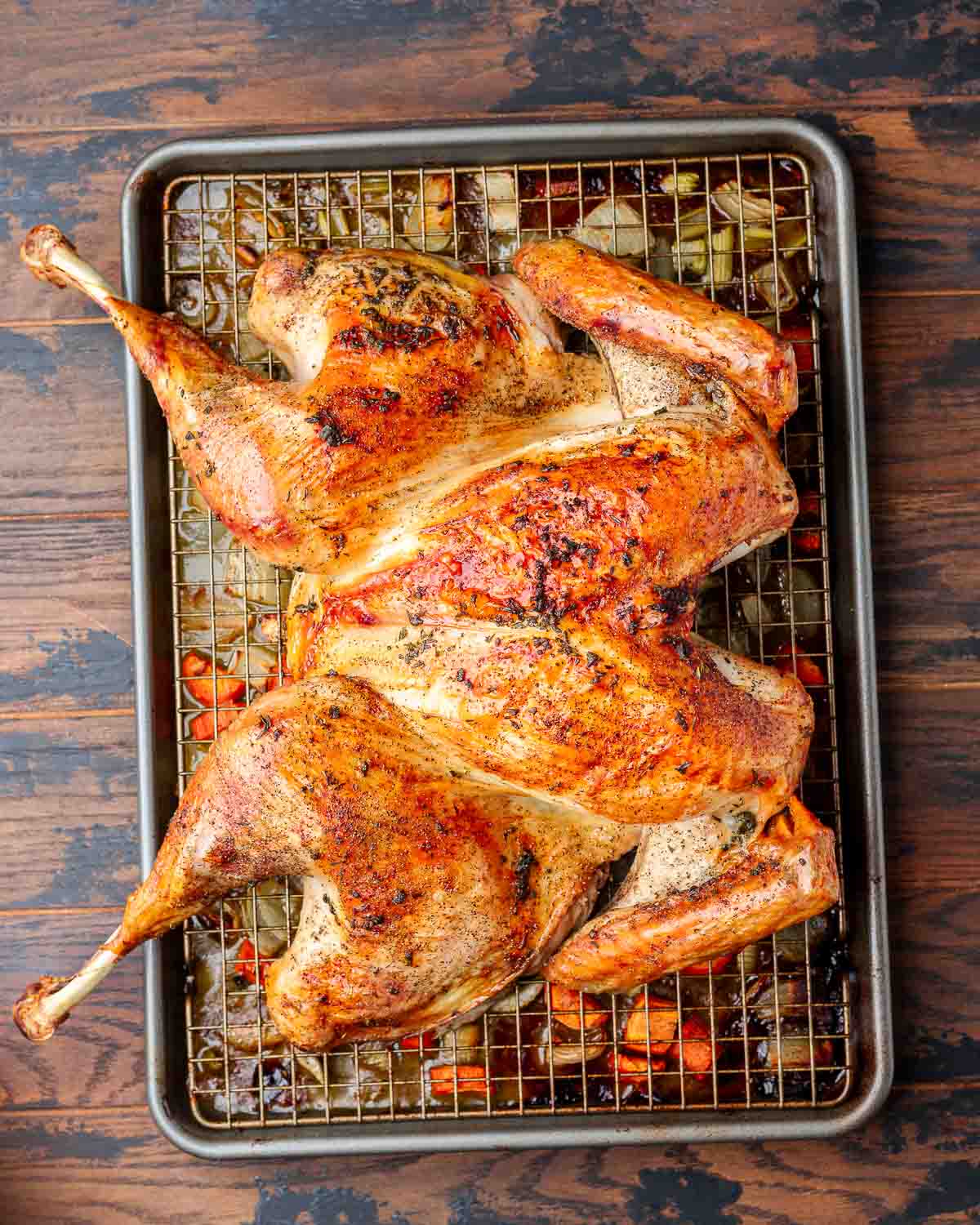 Overhead shot of roasted spatchcock turkey on wire rack lined baking sheet.