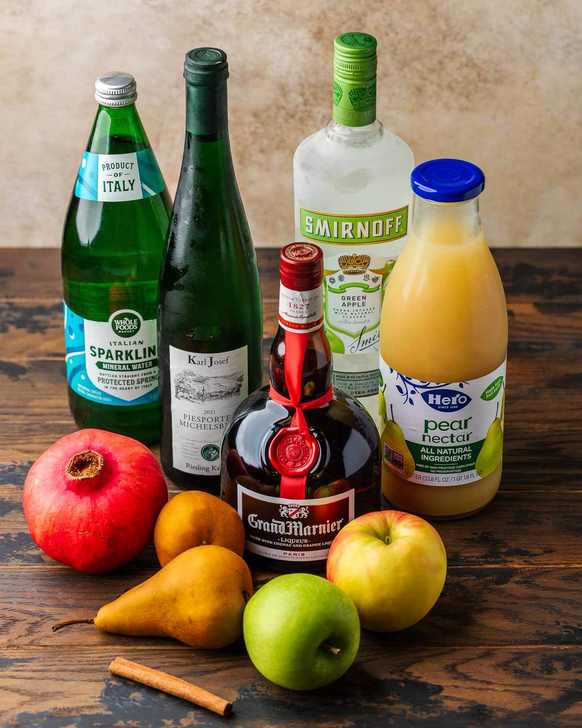 Ingredients shown: sparkling water, reisling, apple vodka, pear nectar, Grand Marnier, pomegranate, pears, apples, and a cinnamon stick.