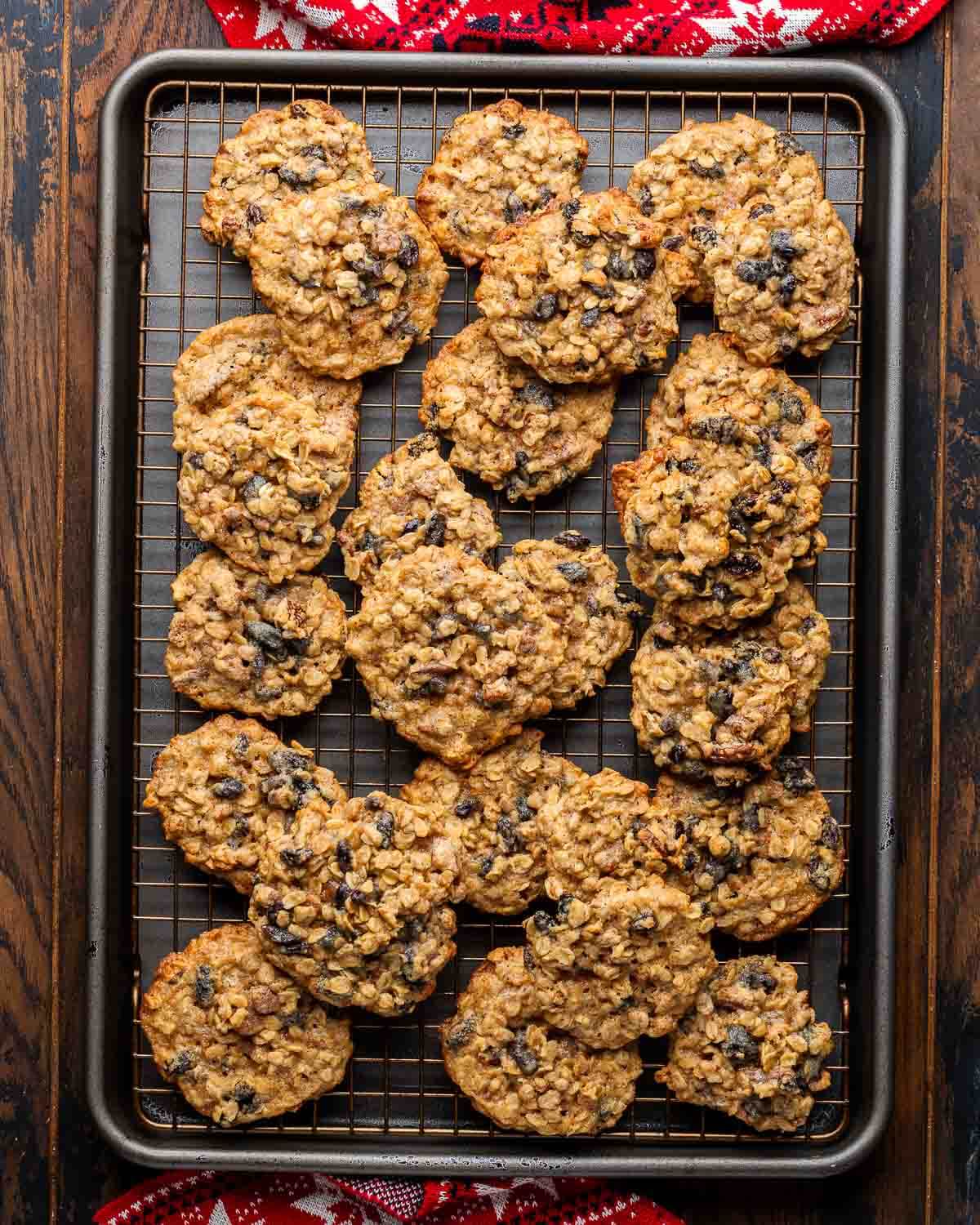 Baking sheet with wire rack and many oatmeal raisin pecan cookies.