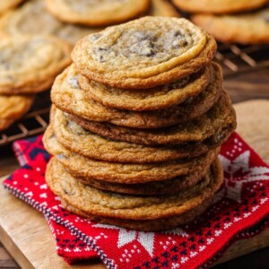 Stack of pan-banging chocolate chip cookies on Christmas towel for featured image.