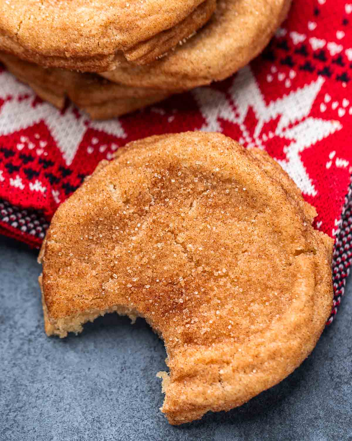 Snickerdoodle with large bite taken out of it on red napkin and blue board.