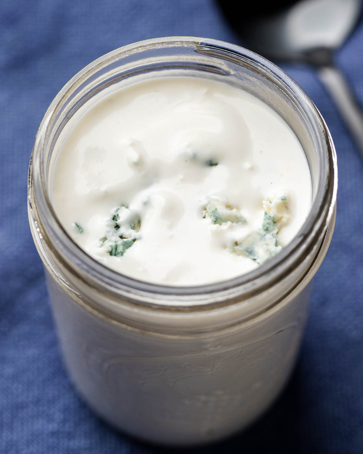 Blue cheese dressing in mason jar on blue napkin.