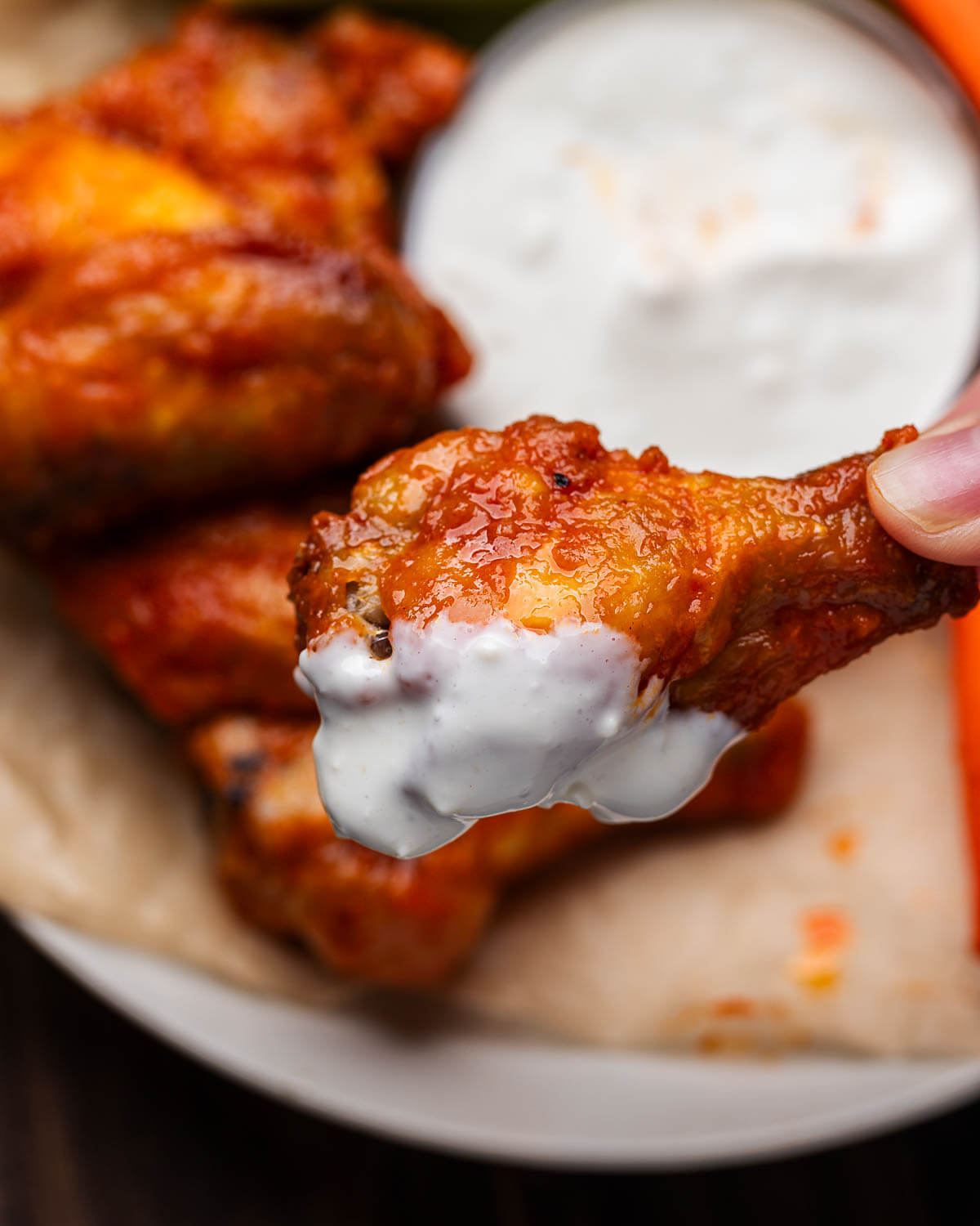 Hand holding wing that was dipped in blue cheese dressing.