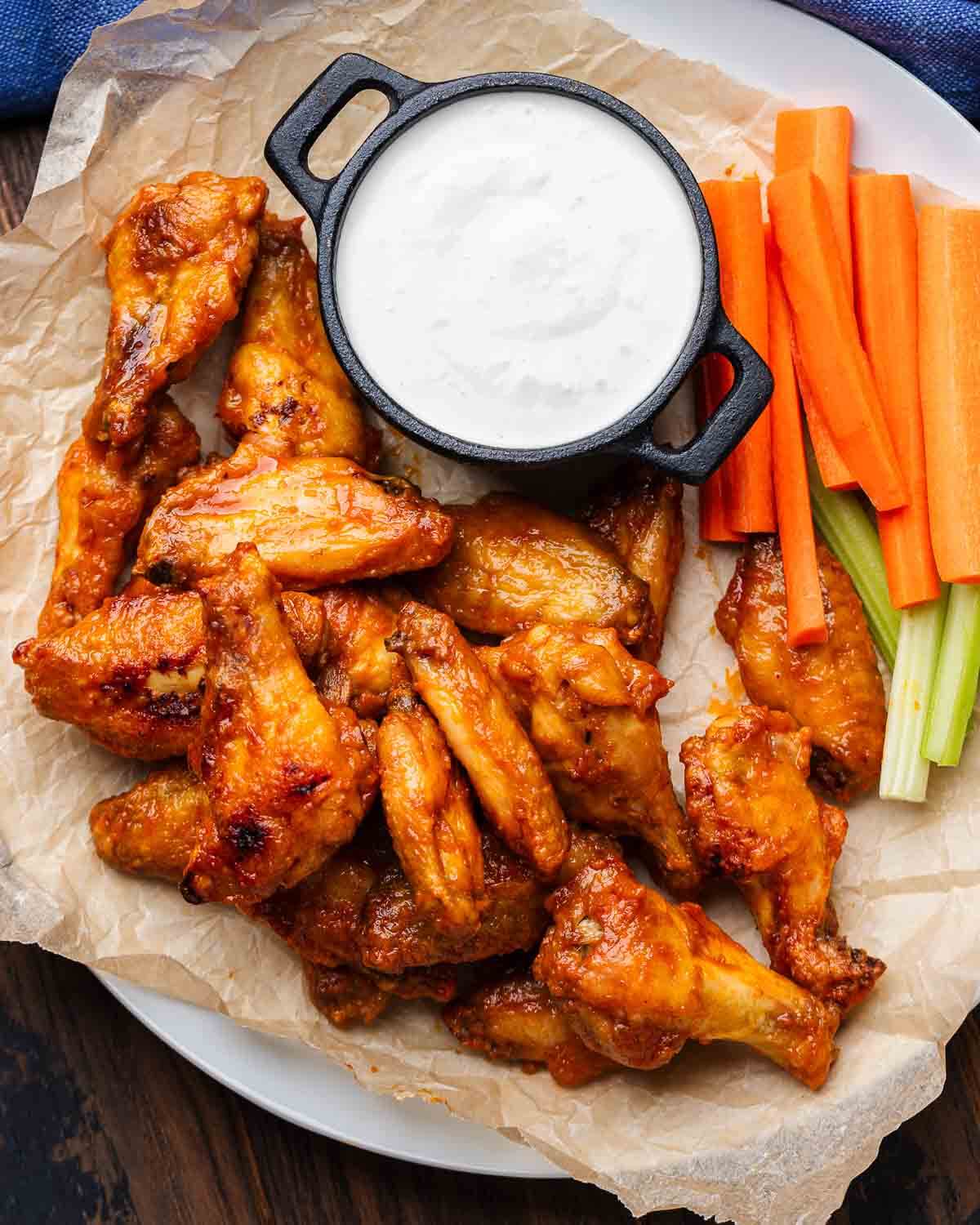 Platter of buffalo wings with blue cheese, celery, and carrots.