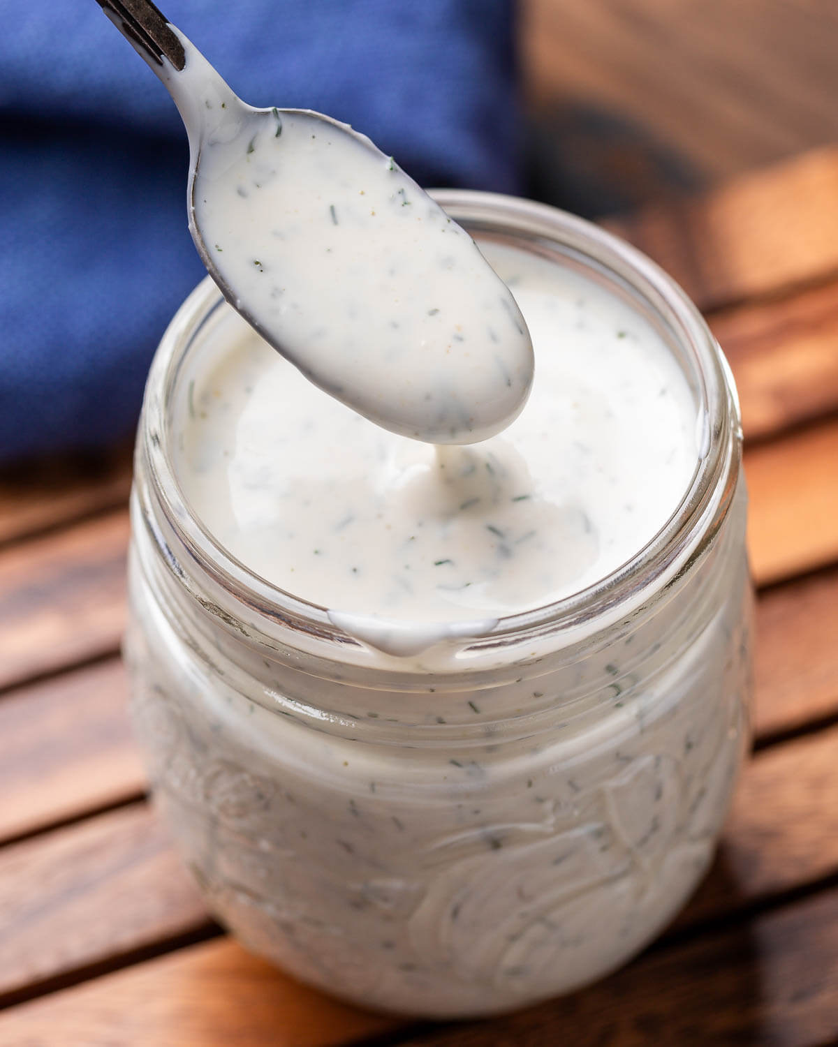 Spoon drizzling ranch dressing into jar.