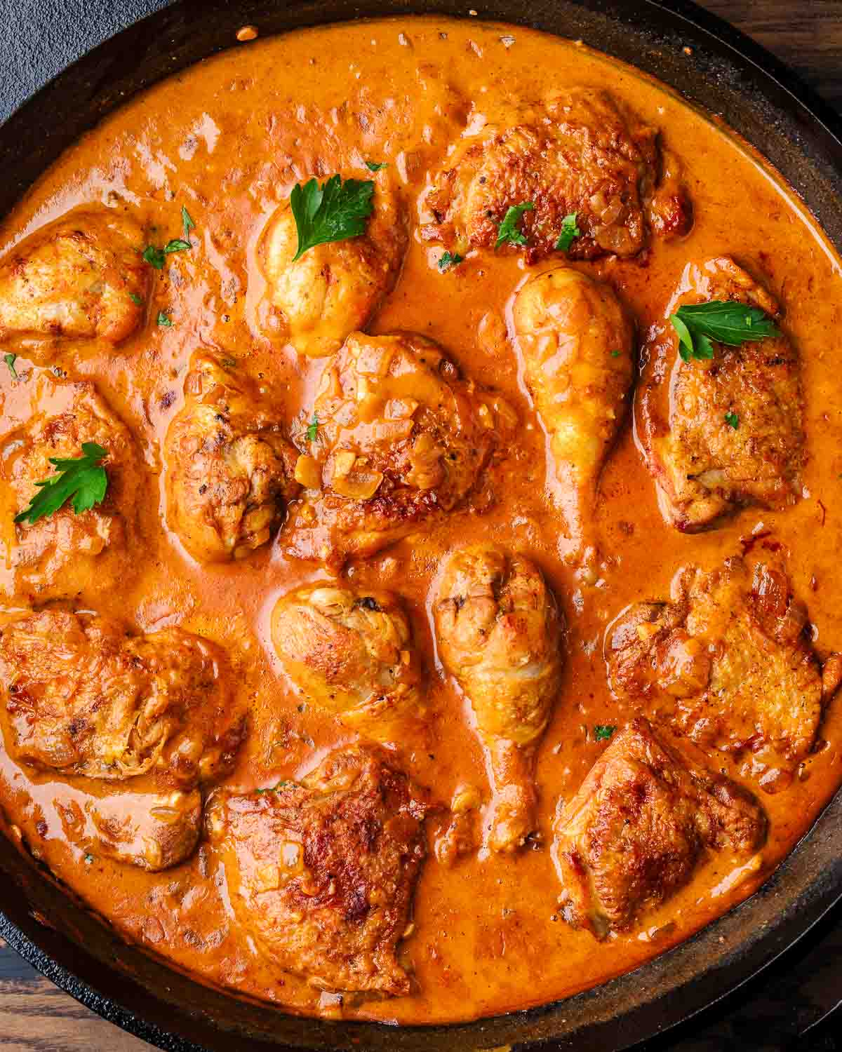 Chicken paprikash in cast iron pan with parsley garnish.