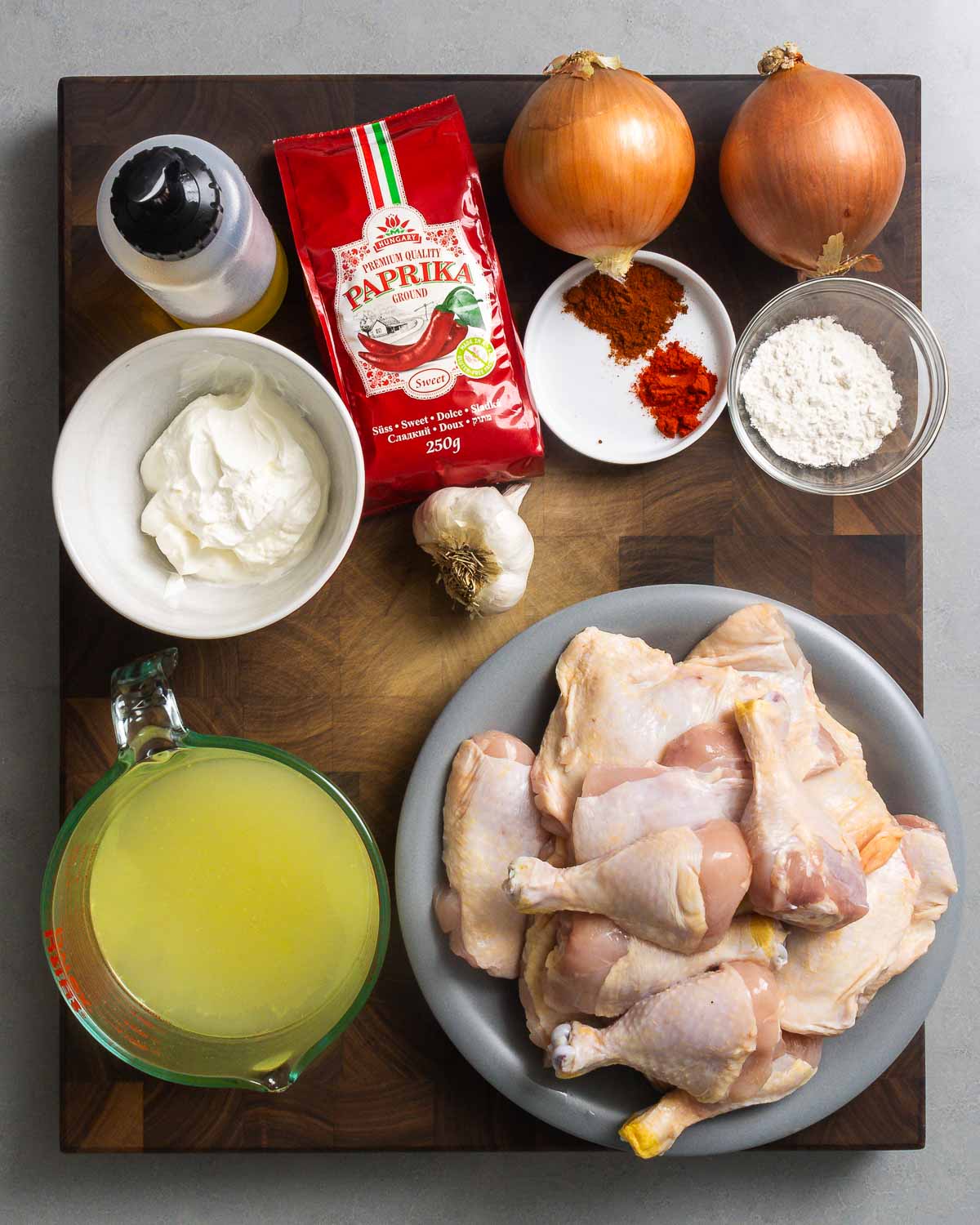 Ingredients shown: olive oil, Hungarian paprikas, onions, flour, sour cream, chicken stock, garlic, and plate of chicken pieces.