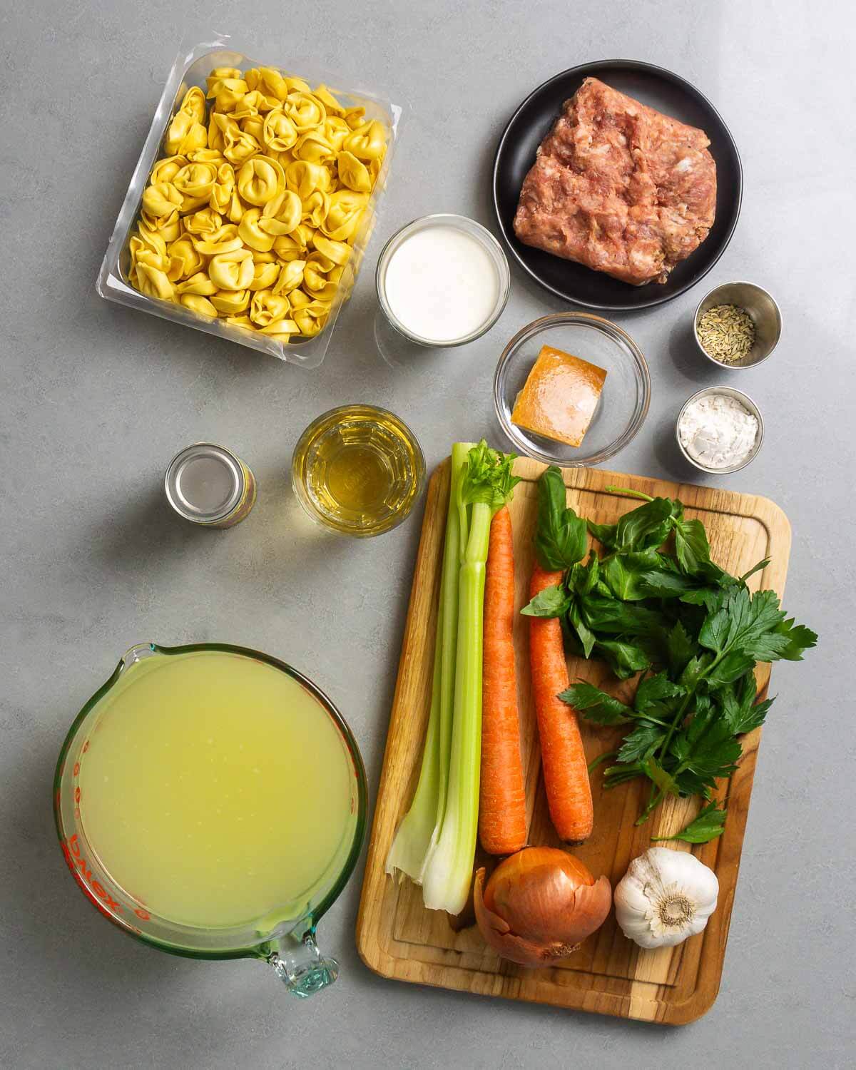Ingredients shown: tortellini, cream ,sausage, tomato paste, wine, parmesan rind, flour, fennel seeds, chicken stock, celery, carrots, onion, garlic, basil, and parsley.