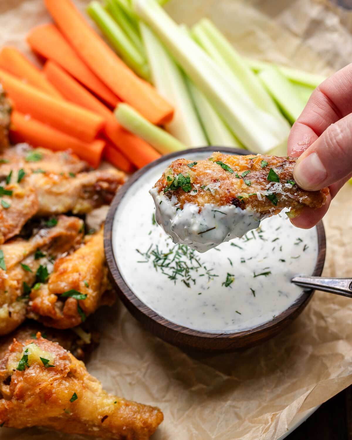 Hand dipping wing into ranch dressing.